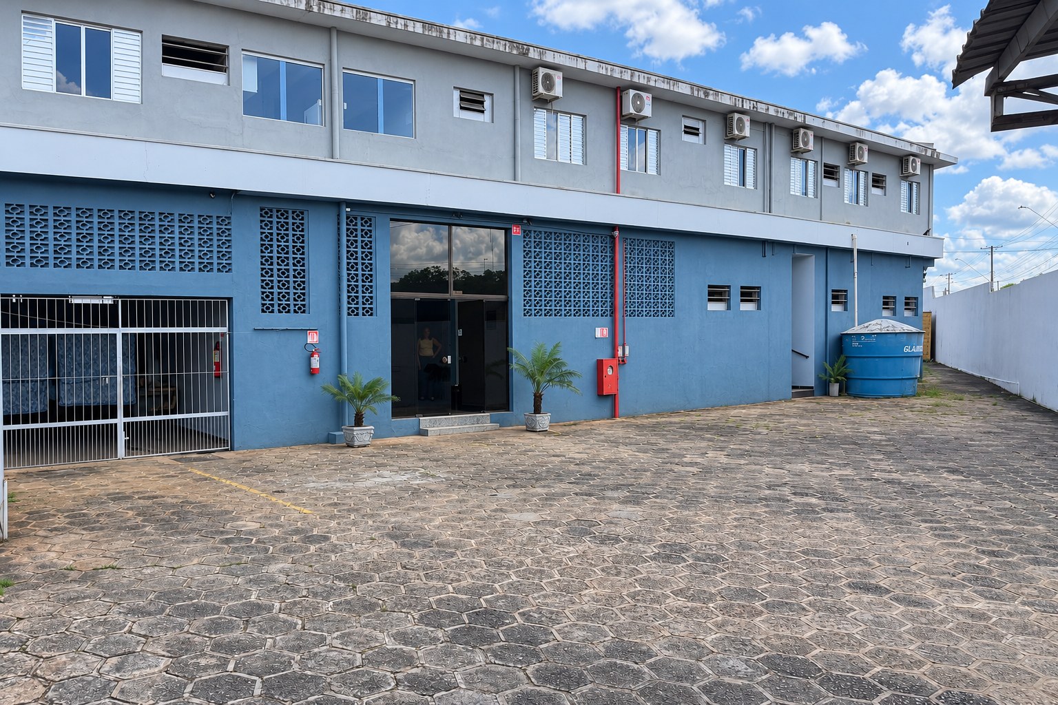 Fachada do Hotel São João, prédio azul e pátio de estacionamento